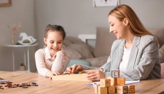 Female psychologist working with girl suffering from autistic disorder in office
